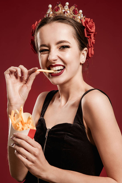 Glamour beautiful sexy woman eating burger over red backround. - Zdjęcie, obraz