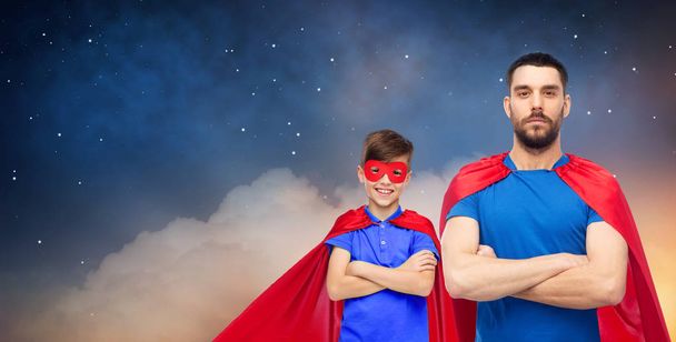 vader en zoon in superheld capes over nachtelijke hemel - Foto, afbeelding