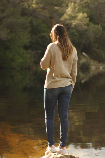 Жінка стоїть на скелі біля озера
 - Фото, зображення