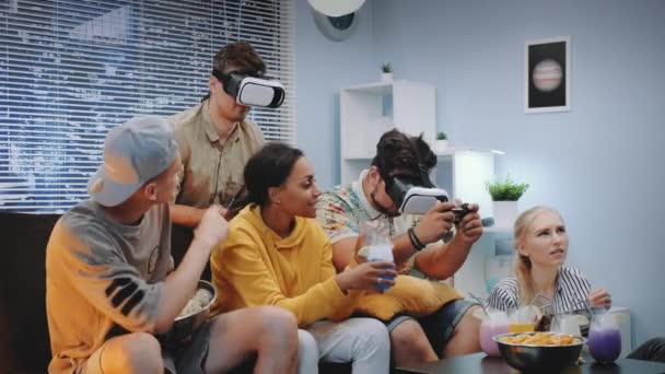 Δύο όμορφα αγόρια που παίζουν παιχνίδι κονσόλας σε γυαλιά εικονικής πραγματικότητας μεταξύ χαρούμενη εταιρεία - Πλάνα, βίντεο