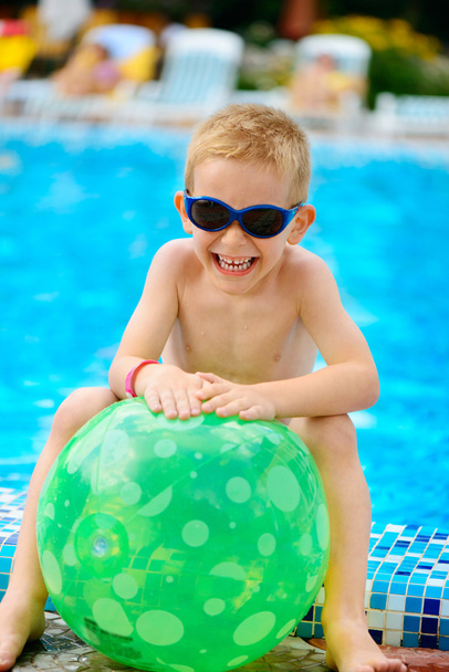 roztomilý chlapec v sluneční brýle sedí u bazénu - Fotografie, Obrázek