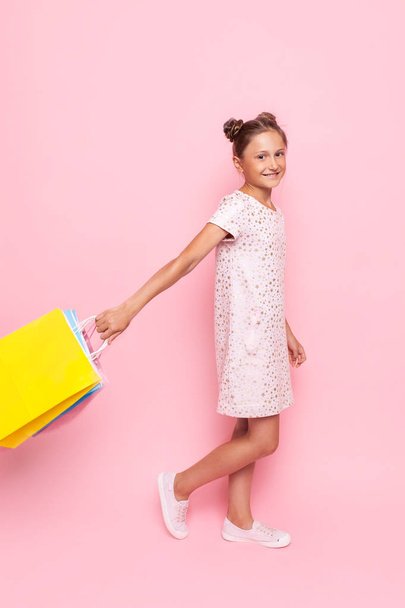 teenage girl in stylish dress with packages in hand makes a purc - Φωτογραφία, εικόνα