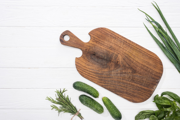 top view of wooden cutting board, cucumbers and greenery  - Photo, Image