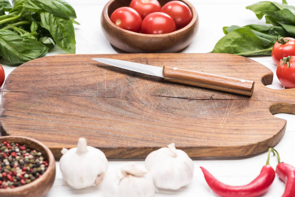 enfoque selectivo de tabla de cortar, tomates cherry, vegetación, chiles, cuchillo, ajos y especias
  - Foto, imagen