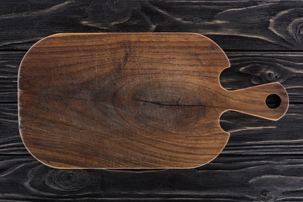 top view of wooden cutting board on black table  - Foto, afbeelding