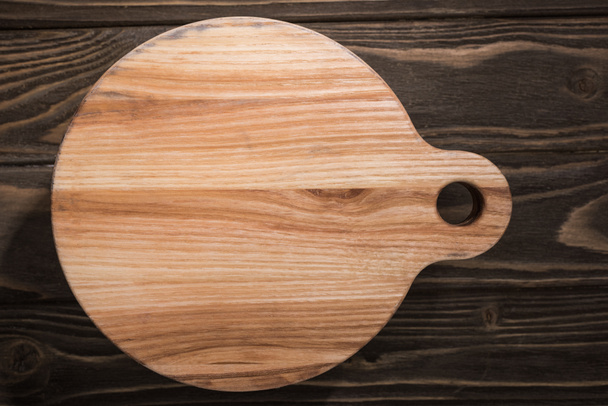 top view of wooden cutting board on brown table  - Foto, afbeelding