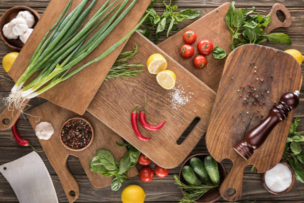 top view of cutting boards, cherry tomatoes, salt, garlics, cucumbers, chili peppers, pepper mill, meat chopper, lemons and spices  - Fotoğraf, Görsel