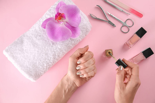 Woman applying nail polish on color background, top view - Foto, afbeelding