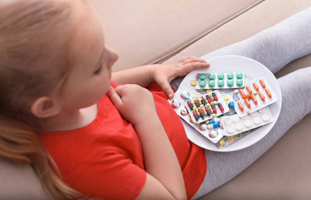 Little child with plate of different pills at home. Household danger - Foto, imagen