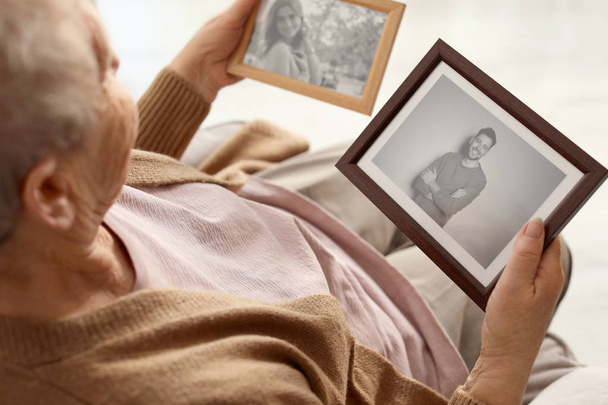 Elderly woman with framed photos at home - Фото, изображение