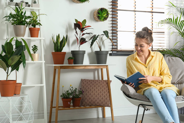 Young woman reading book in room with different home plants - Foto, Imagem