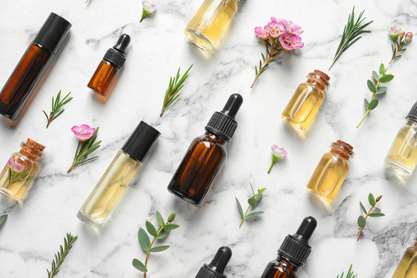 Flat lay composition with bottles of natural tea tree oil on white marble background - Fotoğraf, Görsel