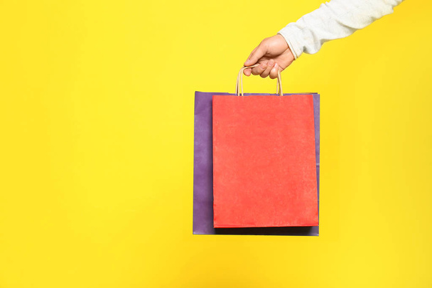 Young man with paper bags on color background, closeup - 写真・画像