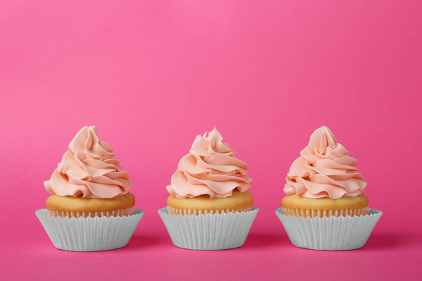 Tasty cupcakes with cream on pink background - Фото, зображення