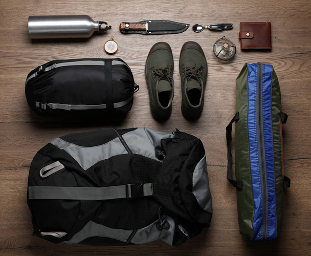 Flat lay composition with different camping equipment on wooden background - Φωτογραφία, εικόνα