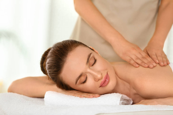 Beautiful young woman enjoying massage in spa salon - Photo, Image