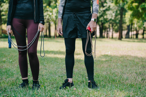 cropped view of mature sportsman and sportswoman holding jump ropes - Photo, Image