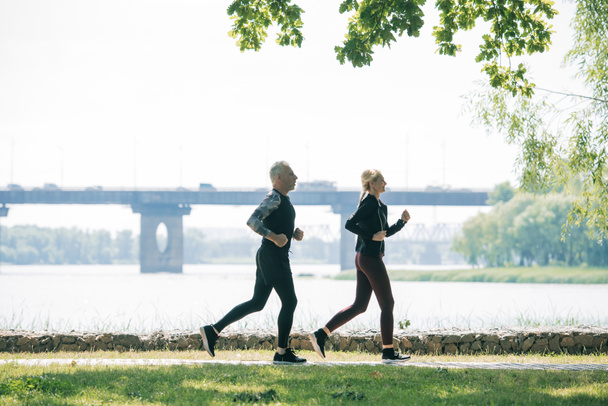 vue latérale de joggeurs sportifs matures courant le long de la rivière dans le parc
 - Photo, image
