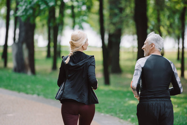 back view of mature, sportive joggers running together in park - Fotoğraf, Görsel