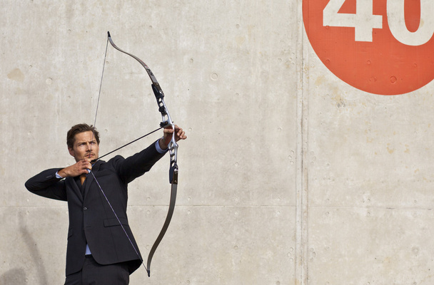 Бизнесмен целится из лука и стрелы в цель
 - Фото, изображение