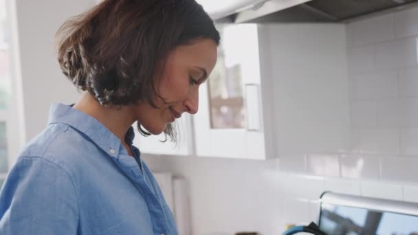 Millennial African American woman standing in the kitchen cooking on the hob, side view, close up - Imágenes, Vídeo
