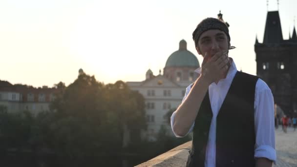 4k - ein Typ, der auf einer Brücke eine Zigarette raucht und bei Sonnenuntergang lächelt, Zeitlupe - Filmmaterial, Video