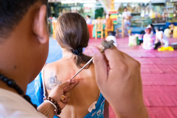 tatuaje de yantra o sak yant, tatuaje sagrado tailandés. maestro dibuja una chica tatuaje incoloro Sak Yant con un aceite especial. Tailandia
. - Foto, Imagen