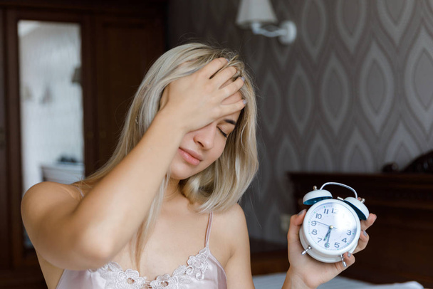 Beautiful young woman wake up in morning annoyed alarm clock holding hand, lifestyle concept. The girl wakes up in the morning. - Fotoğraf, Görsel