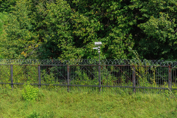 Surveillance camera on a metal fence with barbed wire. - Foto, Imagen