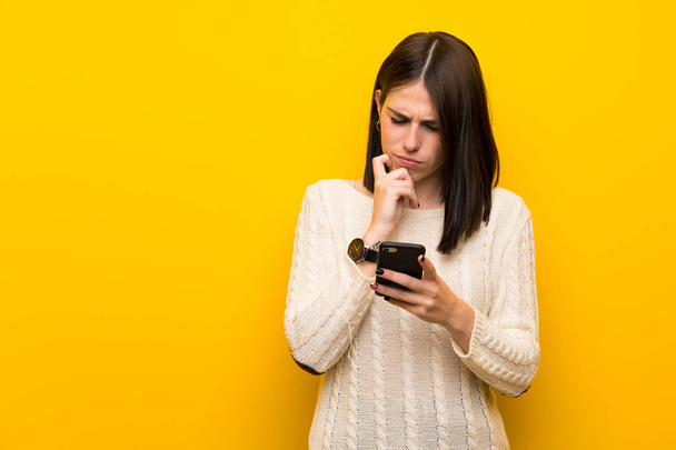 Jovem mulher sobre isolado parede amarela pensando e enviando uma mensagem
 - Foto, Imagem