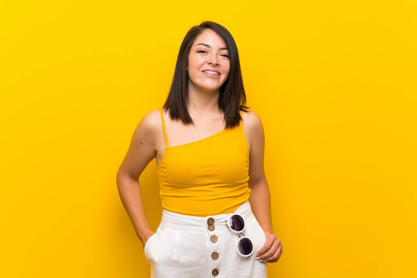 Young Mexican woman over isolated yellow background laughing - Foto, Imagem