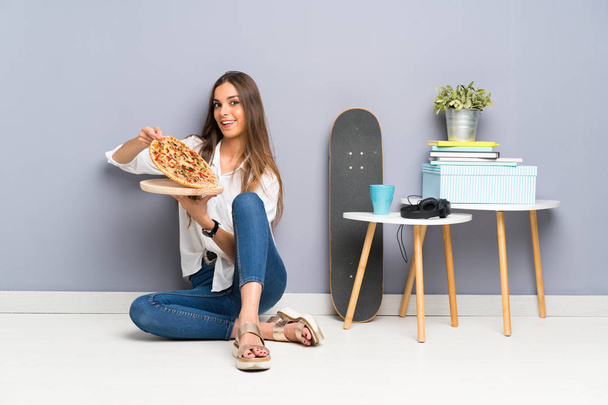 junge Frau sitzt mit einer Pizza auf dem Boden - Foto, Bild