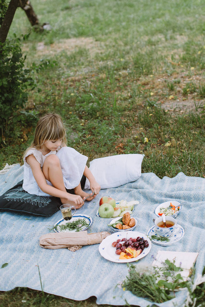 Niña en el jardín con un picnic
 - Foto, imagen