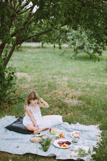 Klein meisje in de tuin met een picknick - Foto, afbeelding