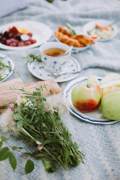 Vista laterale del picnic in giardino con frutta, tè, pane e insalata
 - Foto, immagini