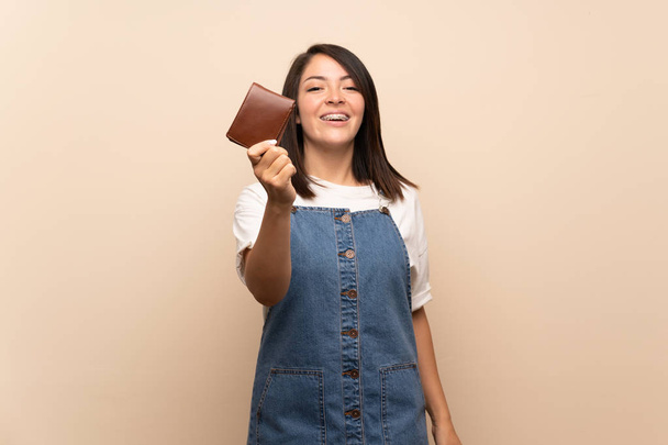 Young Mexican woman over isolated background holding a wallet - Photo, Image