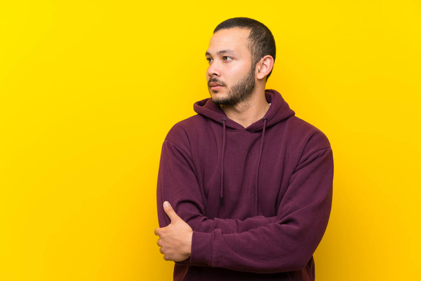 Colombian man with sweatshirt over yellow wall portrait - Zdjęcie, obraz