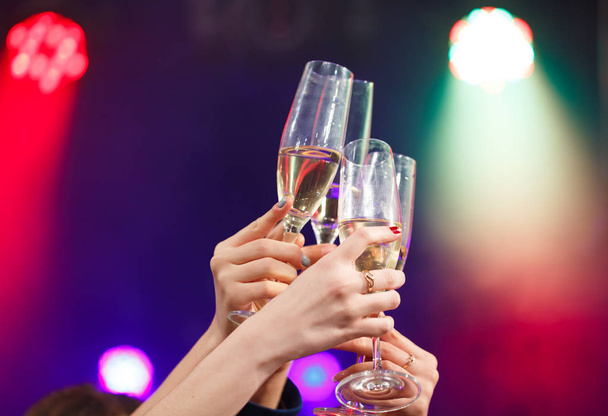 Clinking glasses of champagne in hands on bright lights background. - Photo, Image