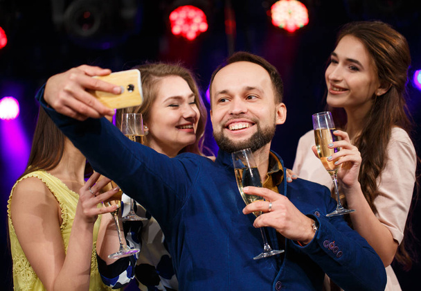 Impreza, święta, technologia, uśmiechnięci przyjaciele z kieliszków szampana i smartphone robienia selfie w klubie. - Zdjęcie, obraz