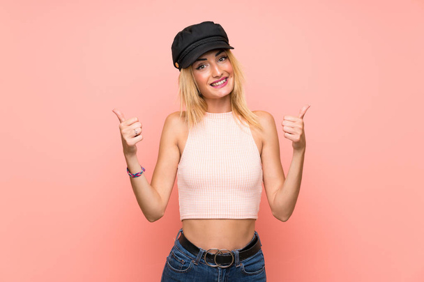 親指のジェスチャーと笑顔の帽子を持つ若いブロンドの女性 - 写真・画像