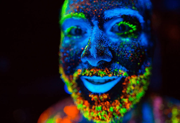 Portrait of a bearded man painted in fluorescent powder. - Photo, Image
