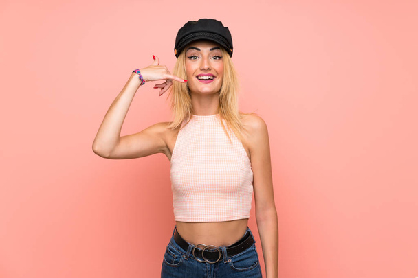 Young blonde woman with hat making phone gesture. Call me back sign - Foto, Bild