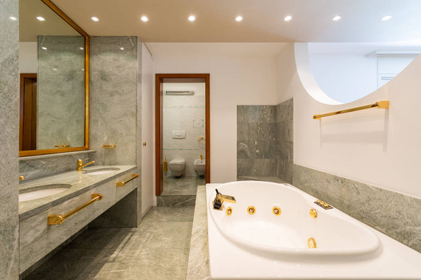 Luxus-Badezimmer mit großer Hydromassage, grünem Marmor und Gold - Foto, Bild