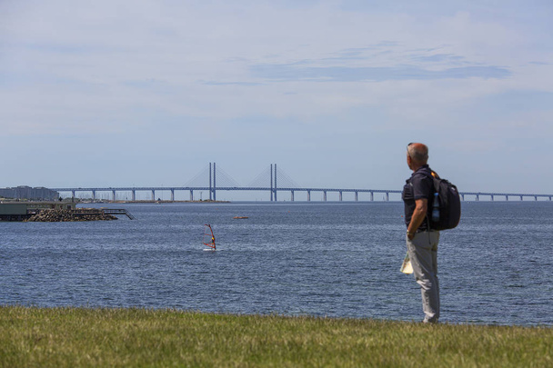 A tourist on the shores of the Baltic Sea looking at the Oresund Bridge, Malmo, Sweden - Photo, Image