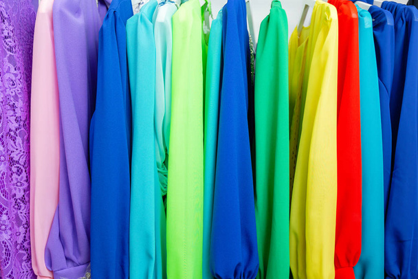 Cocktail jurk. Kleding op hanger in de moderne winkel boetiek. Heldere multi-gekleurde stoffen. concept van winkelen. - Foto, afbeelding