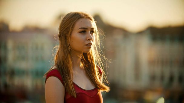 A young inspired woman in red dress standing on the roof - bright sunset - Photo, Image