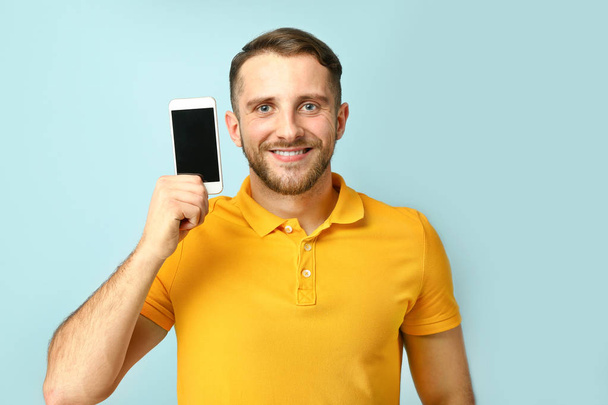 Handsome man with mobile phone on color background - Foto, Imagem