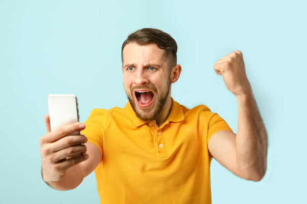 Happy successful man with mobile phone on color background - Zdjęcie, obraz