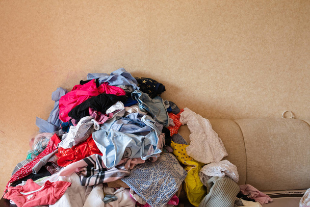 Vista frontal de la ropa dispersa en el sofá en casa
 - Foto, Imagen
