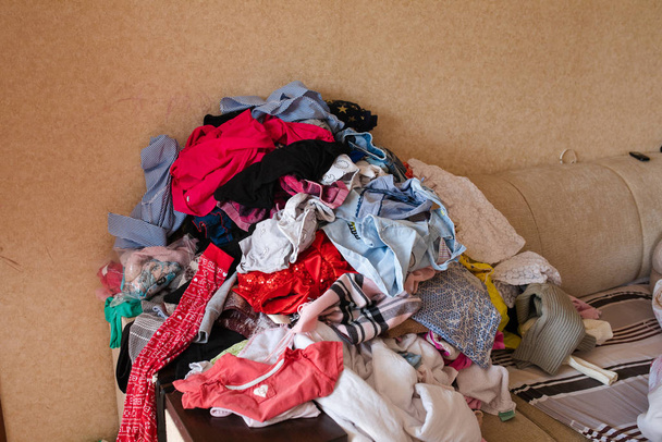 Μπροστινή όψη των ρούχων που είναι διάσπαρτα στον καναπέ στο σπίτι - Φωτογραφία, εικόνα